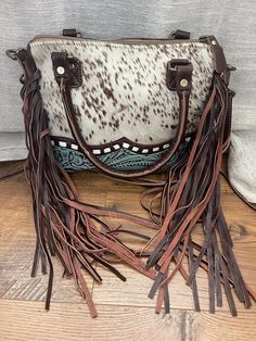 "This lovely bag is a smaller version of our large concealed carry bag. It features fringe on the sides, as well as embossed leather trimming the bottom panel topped with cowhide. There is both top handles and a shoulder or crossbody strap. The back of the purse has a concealed carry pocket, which could also function as a phone pocket. This bag measures 10.5\" wide, 8.5\" tall, and 3\" deep. Please note all hides vary so the pattern may not be exactly as shown." Tas Handmade, Western Bags Purses, Western Style Purse, Purse With Fringe, Raffia Shoes, Leather Fringe Purse, Boho Handbag, Western Bag, Leather Working Patterns