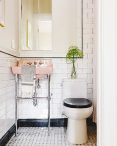 a white toilet sitting next to a pink sink in a bathroom with black and white tiles