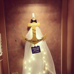 a wedding dress hanging on a wall with lights around it and a cross attached to the back