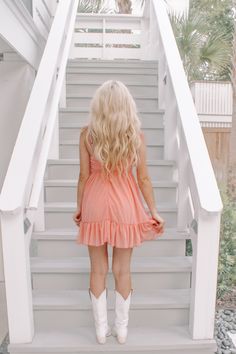 a blonde haired girl in a short dress and cowboy boots is walking up the stairs