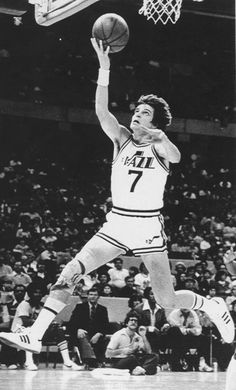 an old black and white photo of a basketball player jumping up to dunk the ball