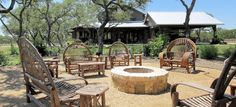 an outdoor fire pit surrounded by wooden chairs