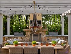 an outdoor dining area with wicker chairs and a table surrounded by potted plants