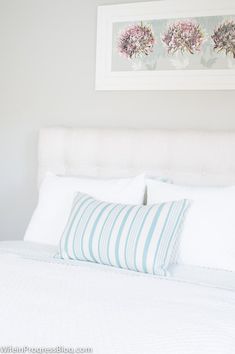 a bed with white sheets and blue striped pillows