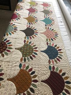 a quilted table runner with multicolored flowers on it