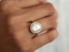 a woman's hand wearing a pearl and diamond ring