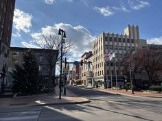 an empty city street with buildings on both sides and flags flying in the air above