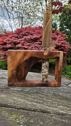 a sculpture made out of wood with rocks in the center and a feather sticking out of it