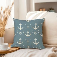 a pillow with an anchor pattern on it sitting on a couch next to a cup