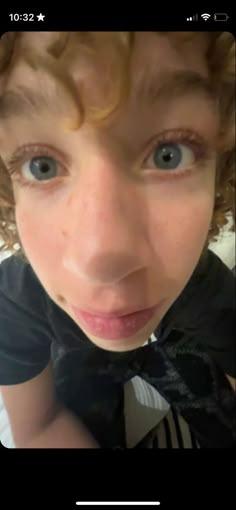 a close up of a child with blue eyes and curly hair wearing a bow tie