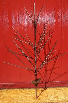 a small metal tree sitting in front of a red door