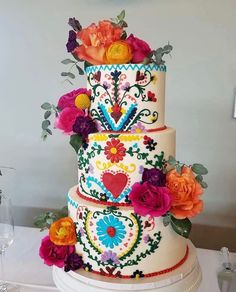 a multi - tiered cake decorated with colorful flowers and leaves on a white table