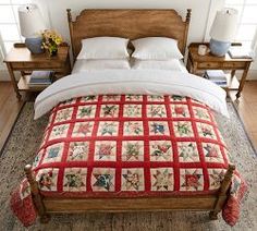 a bed with a red quilt on top of it in a bedroom next to two nightstands