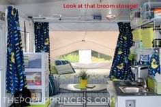 the inside of a camper with blue and yellow curtains, white walls, and green accents