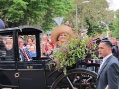 a man in a suit and hat riding on a horse drawn carriage with people watching