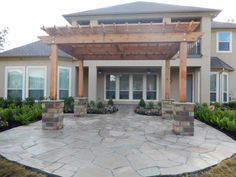 an outdoor patio with stone walkway and pergolated area in front of the house