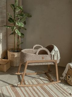 a wicker baby's rocking chair next to a potted plant