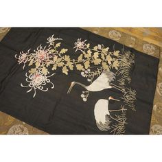 two cranes and flowers on a black background with gold foilwork around the edges,