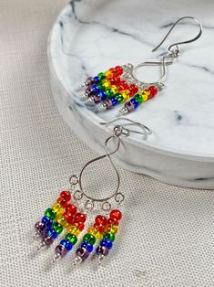 a pair of colorful beaded earrings sitting on top of a white table next to a plate