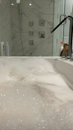 a bathtub filled with lots of foam next to a shower