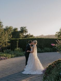 a bride and groom standing in front of a hedged garden at their wedding reception