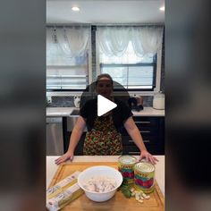 a woman standing in front of a cutting board with food on it