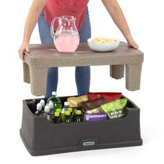 a woman standing next to a table with food and drinks on it in front of her