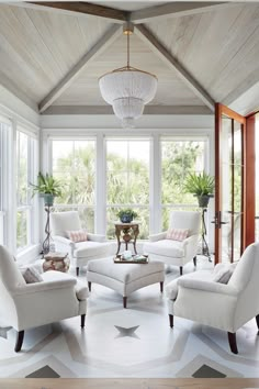 a living room filled with white furniture and lots of windows