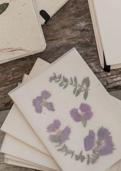 four cards with pressed flowers on them sitting on a table