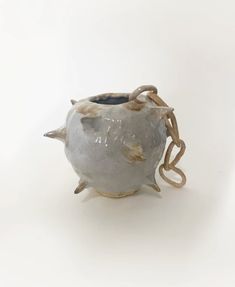 a white ceramic vase with an animal head on it's side and a chain around the neck