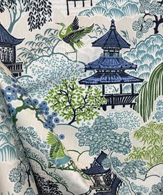 a blue and green fabric with pagodas, trees, and birds on it's side