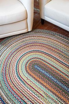 a multicolored rug on the floor in a living room with two white chairs