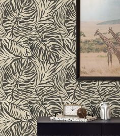 a giraffe and zebra print wallpaper in a living room with a painting on the wall