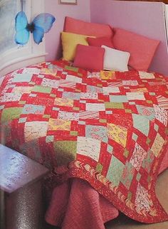 the bed is made up with colorful quilts and pillows