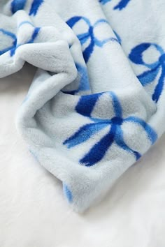 a blue and white blanket laying on top of a bed next to a stuffed animal