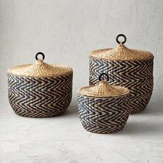 three woven baskets with handles and lids on the top, one is blue and white