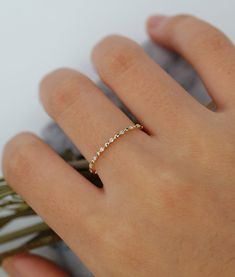 a woman's hand with a gold ring on her finger and the band has five small diamonds