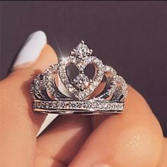 a close up of a person holding a ring with a heart shaped diamond on it