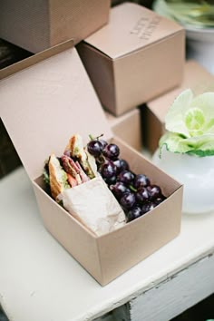 two open boxes filled with food sitting on top of a table next to a vase