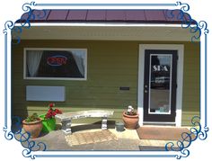 the front door of a motel with flowers and potted plants