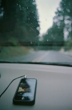 a cell phone sitting on the dashboard of a car next to a window with trees in the background