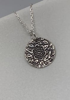 This beautiful floral circle silver necklace pendant has been entirely handmade using .999 fine silver. It has been cut from fine silver precious metal clay, textured, fired and oxidized. The pendant hangs from a sterling silver diamond cut cable chain. This unique and handmade necklace features an embossed floral leaf branch pattern. Pendant size: approximately 1/2 x 1/2 inches Chain length: adjustable at 16 and 18 inches can also be customized to whatever length needed The necklace is sent in Silver Etched Necklace With Flower Pendant, Silver Etched Nature-inspired Necklaces, Silver Engraved Nature-inspired Necklace, Nature-inspired Sterling Silver Etched Jewelry, Nature-inspired Silver Etched Necklaces, Nature-inspired Etched Sterling Silver Jewelry, Etched Sterling Silver Necklaces, Artisan Silver Etched Necklace, Silver Etched Sterling Silver Necklace