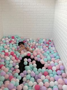 a room filled with lots of balloons floating in the air next to a white brick wall