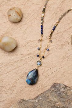 Discover the vibrant and stunning colors of the Blue Moon Collection in this eclectic necklace! Gold Filled (Lead & Nickel Free) Lapis Lazuli, Pyrite, Sodalite, Labradorite, Mother Of Pearl, Abalone 30.5-32.5" adjustable length, with gold filled lobster claw clasp We hand select our natural materials, thus there may be slight variations in color and/or size that will not detract from the overall aesthetic. Our unique handcrafted designer jewelry for women is made in America, each design created Blue Labradorite Bohemian Jewelry, Bohemian Blue Labradorite Jewelry, Bohemian Blue Labradorite Necklace, Blue Teardrop Pendant Necklace With Natural Stones, Blue Spiritual Necklace With Gemstone Accents, Blue Natural Stones Teardrop Pendant Necklace, Bohemian Lapis Lazuli Teardrop Jewelry, Artisan Blue Necklace With Gemstone Accents, Artisan Blue Teardrop Pendant Necklaces