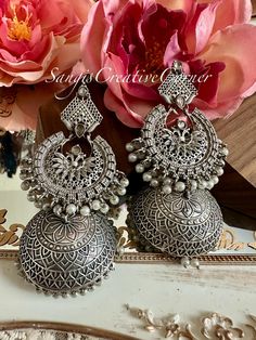 Minimalism at its finest! This is a simple, no fuss  brass-based textured silver tone finish jhumka style earrings which has a very contemporary style. The combination of plain matte silver polish look with the carvings and the pearl embellishments is just the right addition to any everyday outfit. Again, It's the right balance you need to make a statement but not over the top.   Also, very light on the ears! the craftsmanship has been perfected with these simple jhumkas.    Highlights of the piece: ** Dangled full jhumka style earrings with height: 4 inch ** Pushback in the back for the earrings ** Free shipping over $35 The measurements are approximate.  If you have any further questions, feel free to reach out to us. Care Instructions  Highlights: Protect your Jewellery from Sharp Blows Silver Fusion Bridal Earrings With Intricate Design, Handmade Silver Fusion Style Jhumkas, Handmade Silver Fusion Jhumkas, Festive Silver Pierced Earrings, Traditional Silver Pearl Earrings, Traditional Silver Dangle Pearl Earrings, Traditional Silver Sterling Silver Pearl Earrings, Traditional Silver Sterling Pearl Earrings, Silver Round Pearl Earrings For Celebration