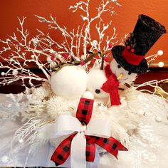 two snowmen with hats and scarfs on top of a white tablecloth covered surface