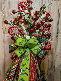 a christmas wreath with candy canes and ornaments hanging on a wooden wall in front of a door