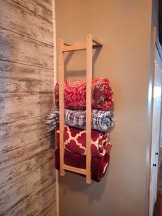 a stack of blankets sitting on top of a wooden shelf next to a wall mounted towel rack