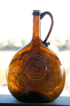 a brown glass vase sitting on top of a window sill