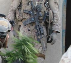 two soldiers in uniform are talking to each other while one is holding a plant and the other is looking at another soldier